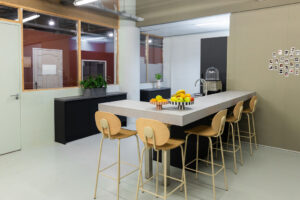 Moderne kantoorkeuken aan de Johan Huizingalaan met hoge tafel, barkrukken en een fruitschaal.